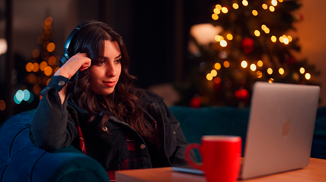 A young woman is relaxing at home and using her laptop in the living room during Christmas